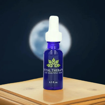 Blue bottle of Vitamin A Complex Nighttime Serum by Vital Therapy for skincare with moonlit backdrop.