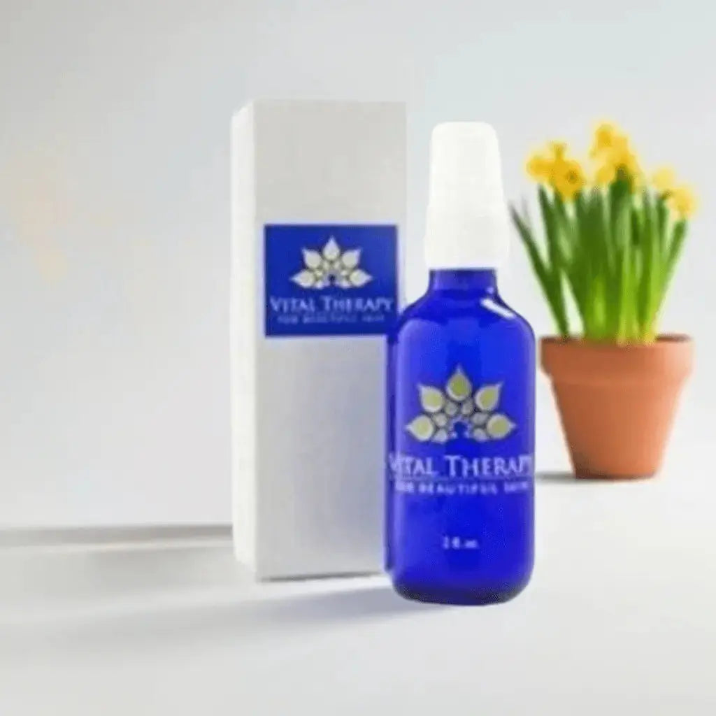 Blue bottle of Healing Cream with box, skincare product in front of potted yellow flowers, 2 oz, made in the USA.