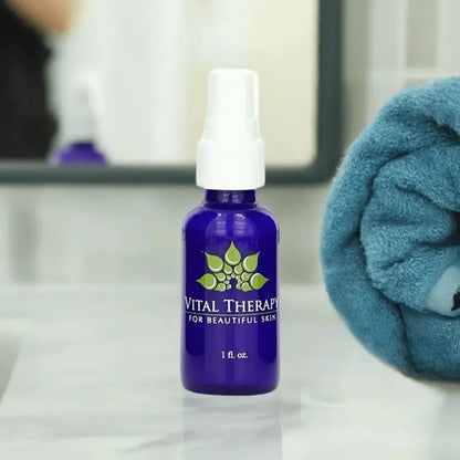 Blue bottle of Vital Therapy skin lightening lotion on a bathroom counter with a towel in the background.